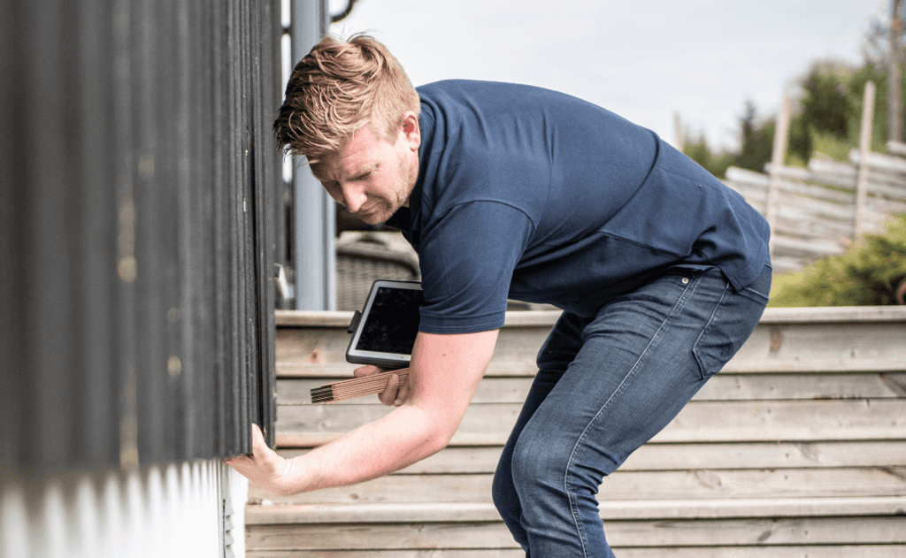 En ansatt i Takstcon på et takstoppdrag utenfor et hus.