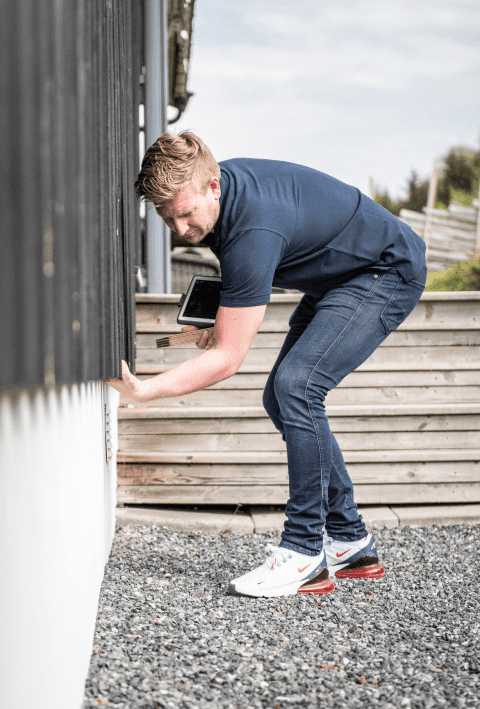 En ansatt i Takstcon på et takstoppdrag utenfor et hus.