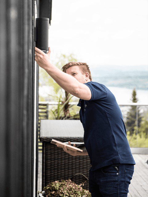 En ansatt i Takstcon på et takstoppdrag utenfor et hus.