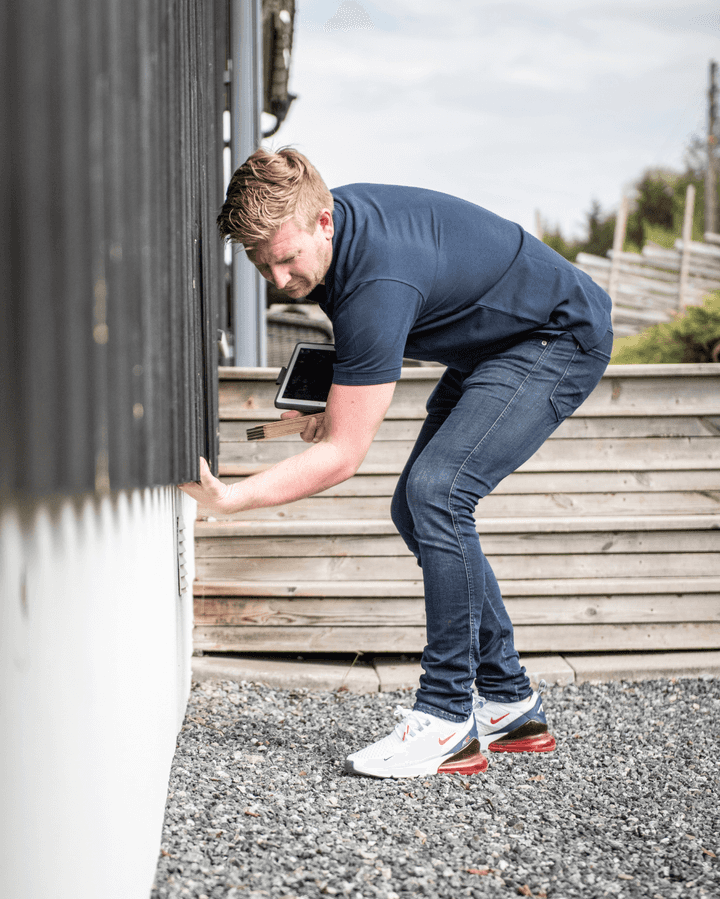 En ansatt i Takstcon på et takstoppdrag utenfor et hus.